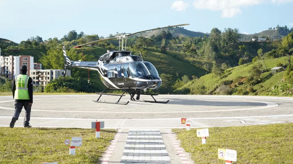 Toma frontal del Helicóptero de Montecielo Fly estacionado en helipuerto al lado izquierdo un operador acercándose a el