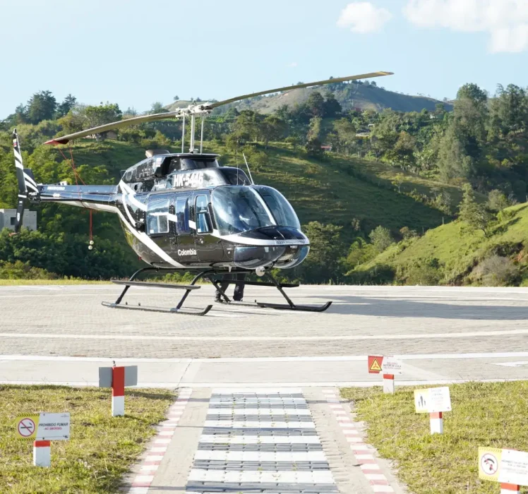 Toma frontal del Helicóptero de Montecielo Fly estacionado en helipuerto al lado izquierdo un operador acercándose a el